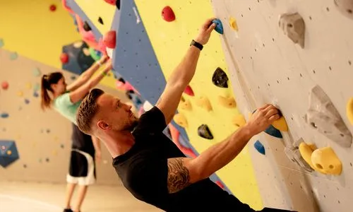 Ein trainierter Mann, welcher an der Boulder Wand hängt.