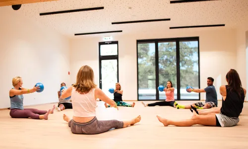 Ein heller, freundlicher Raum mit großem Fenster in welchem ein Gruppen Training abgehalten wird.