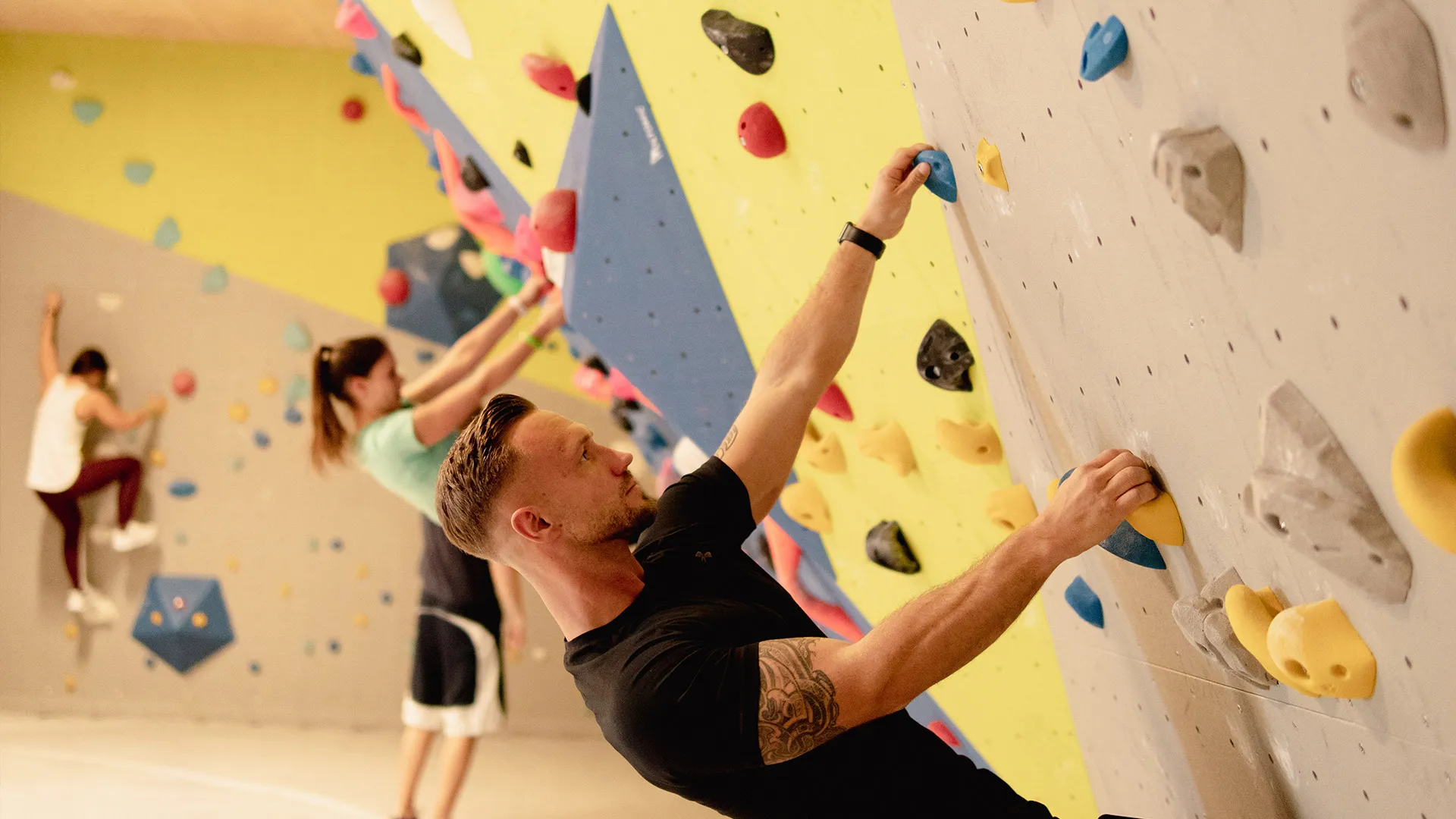 Ein trainierter Mann, welcher an der Boulder Wand hängt.