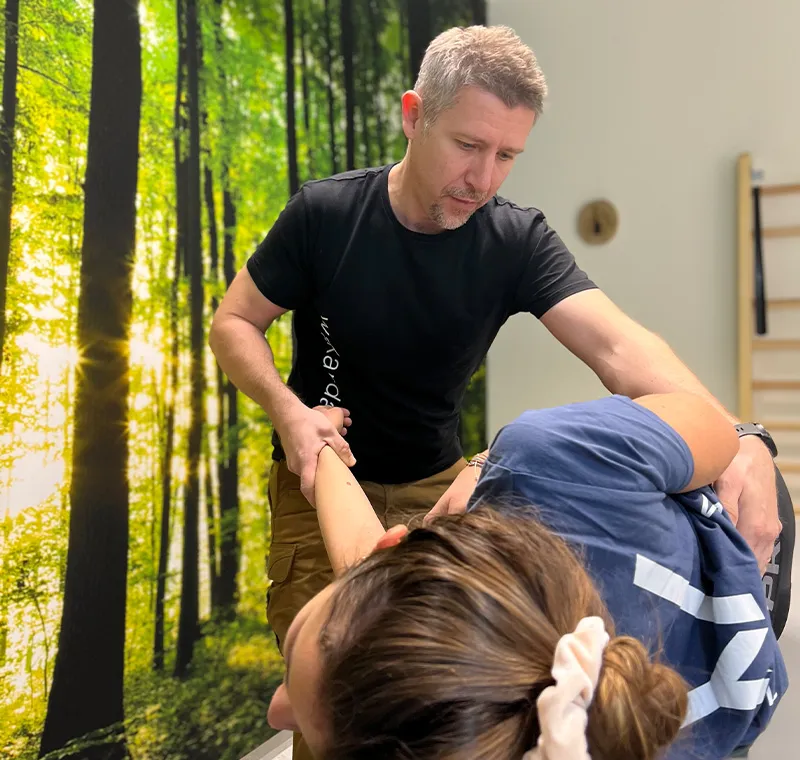 Physiotherapeut Matthias führt eine Behandlung bei einer Dame durch.